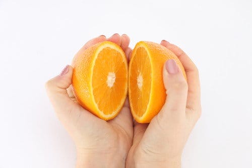 スペインの白い背景にオレンジを持った女性の手。