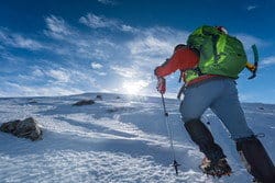 スペインでバックパックを背負って雪山をハイキングする男性。