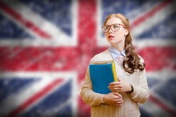 女の子がイギリスの国旗の前で本を持っています。