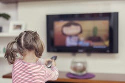 スペインのテレビの前でリモコンで遊ぶ少女。