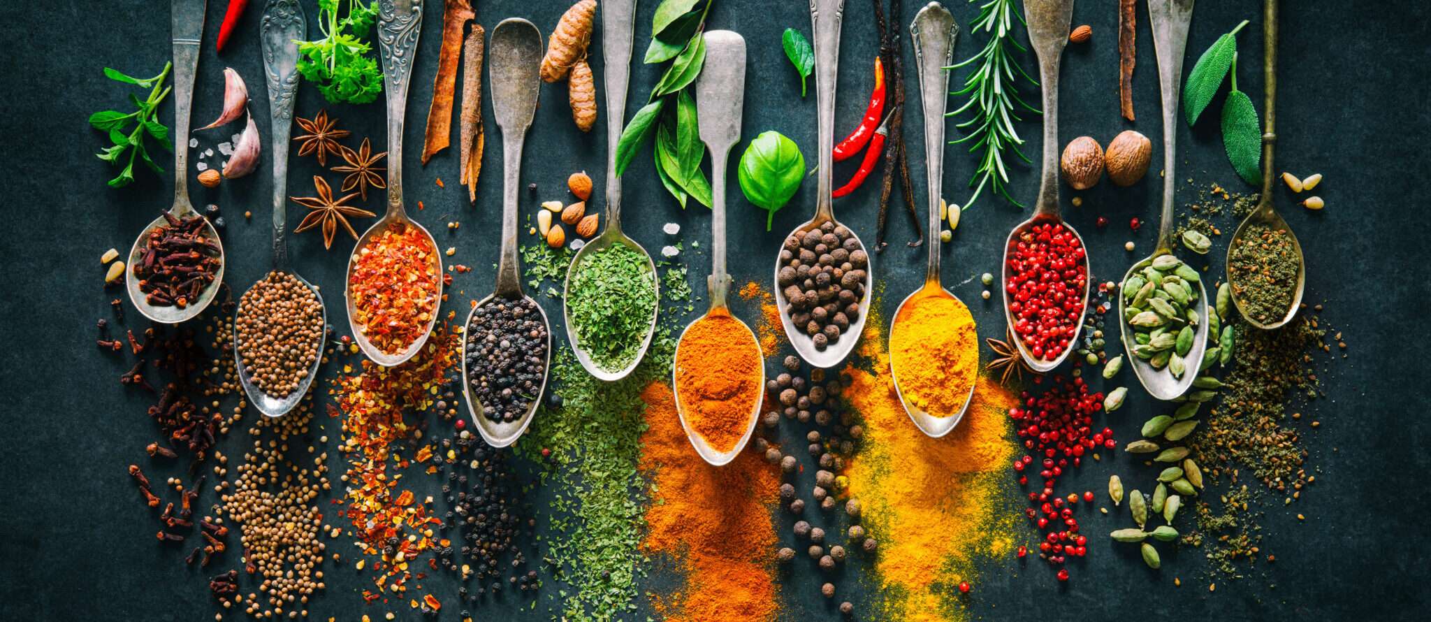 暗い背景にスペインのスパイスとハーブをスプーンで。