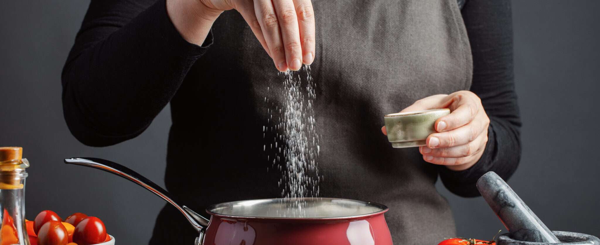 スペインで野菜の入った鍋に塩をまぶしている女性。