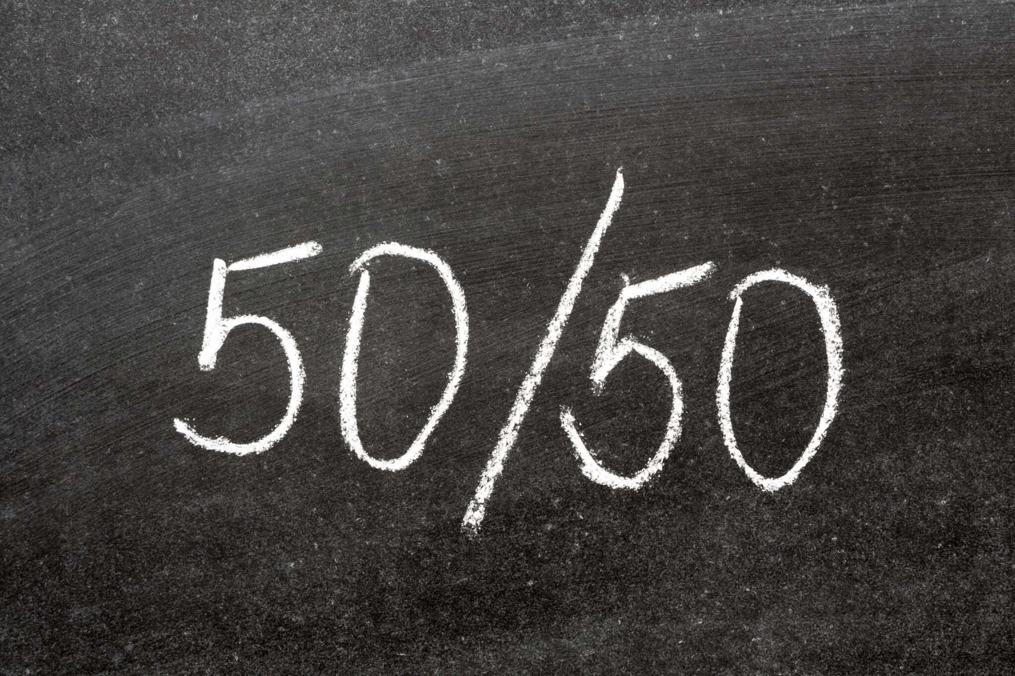 黒板に白いチョークで書かれた「50/50」という文字がスペインに囲まれています。 黒板に白いチョークで書かれた「50/50」という文字がスペインに囲まれています。