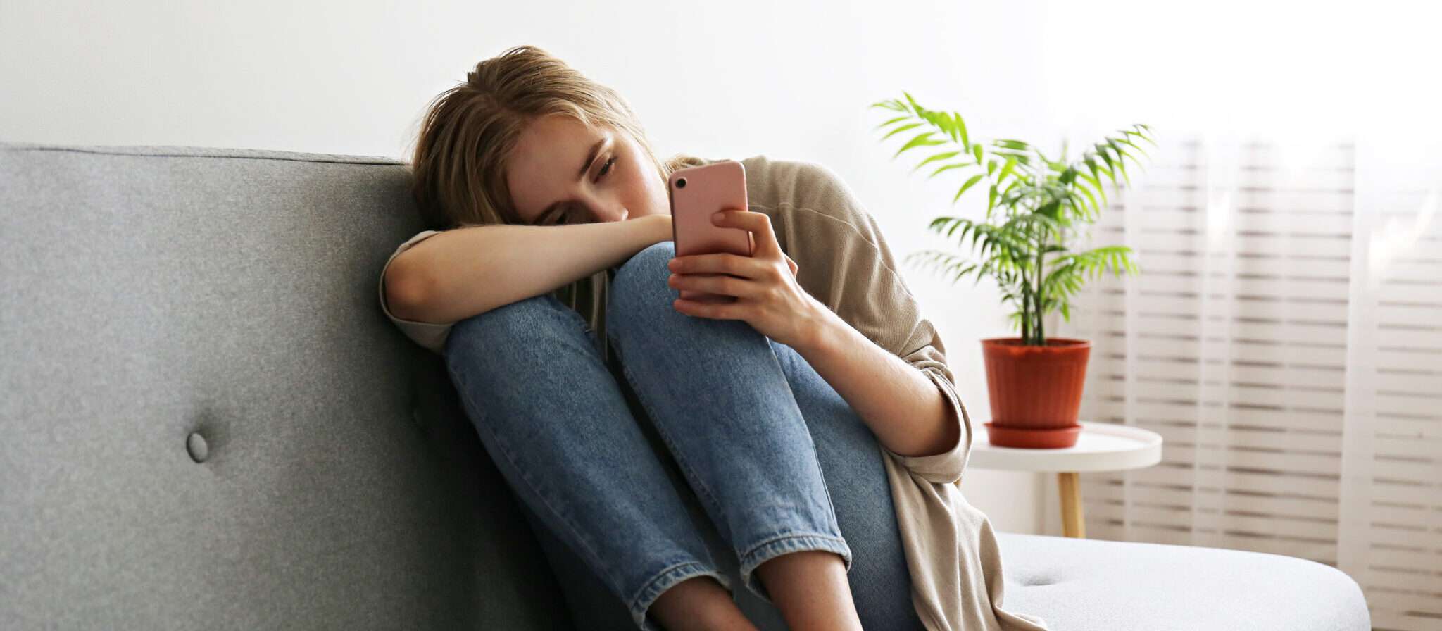 スペインで女性が携帯電話を手にソファに座っている。 スペインで女性が携帯電話を手にソファに座っている。