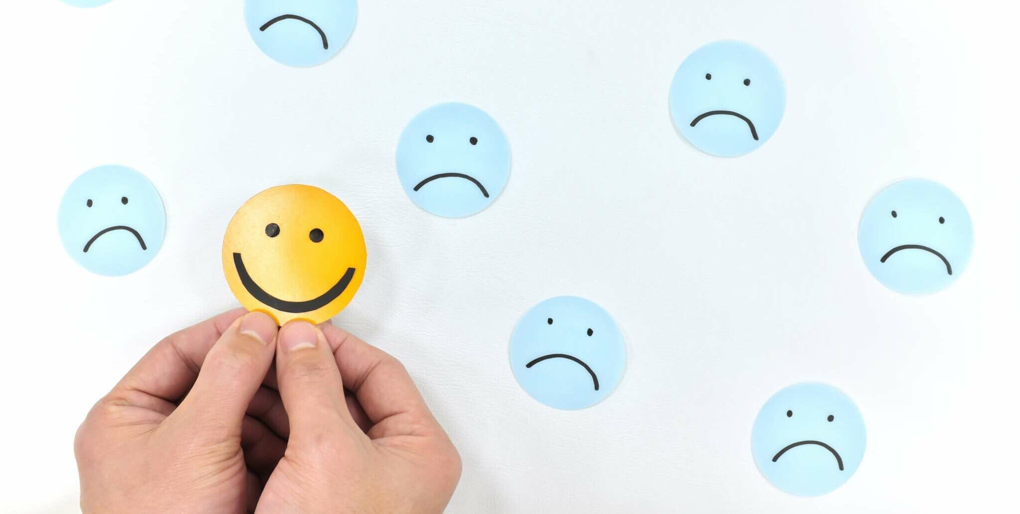 スペインの白い壁にスマイリーフェイスのステッカーを持つ手。