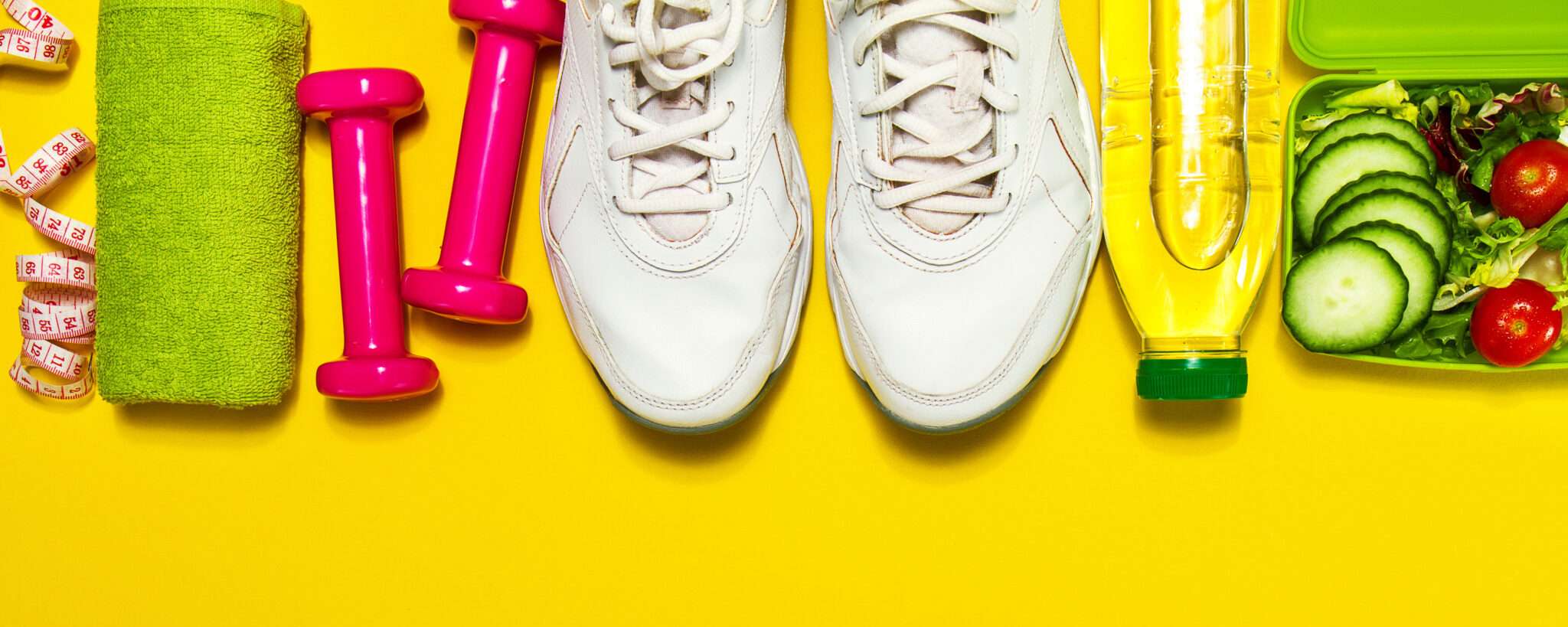 黄色の背景にダンベルと水のボトル。