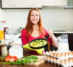 女性が卵の前でフライパンを持ち、スペイン風の食事を準備しています。