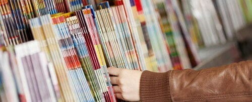 書店の棚からスペインの雑誌を手に取る人。