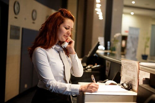 スペインのホテルのデスクで電話で話す女性。