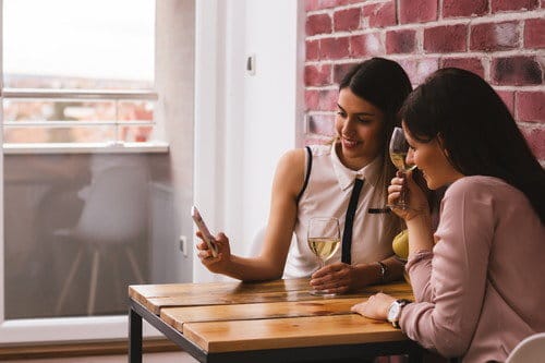 スペインでテーブルに座って携帯電話を見ている 2 人の女性。