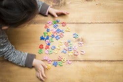 スペインの木製テーブルの上で小さな女の子が文字で遊んでいます。