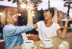 スペインのカフェでハイタッチを交わす 2 人の女性。