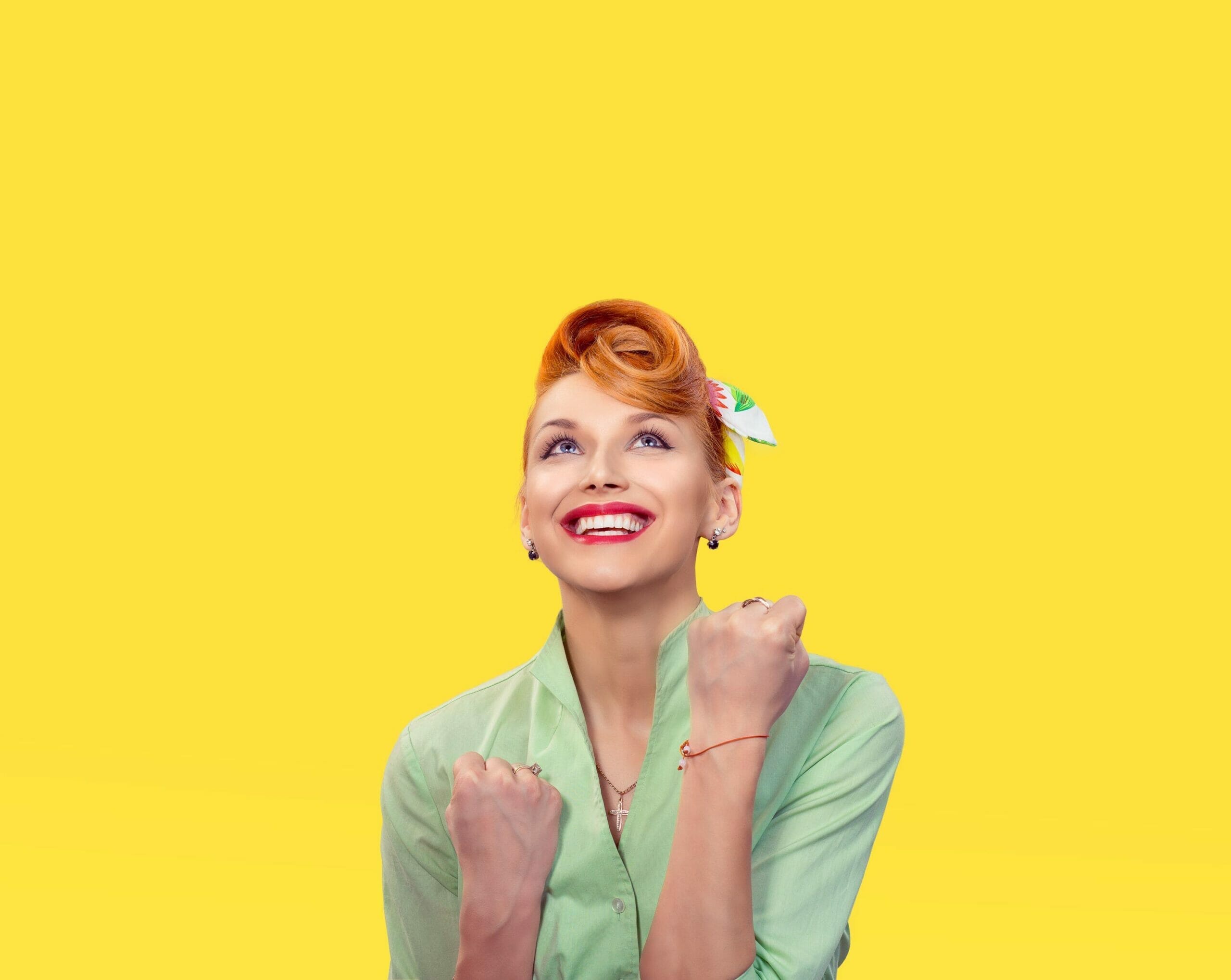 スペインで、黄色の背景に赤い髪の女性が拳を上げてポーズをとっている。