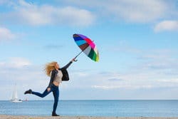 スペインのビーチで若い女性が傘を持ってジャンプしている。