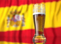 Un vaso de cerveza frente a una Bandera española.