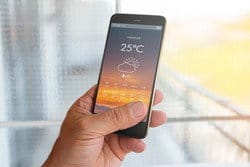 男性が天気アプリを入れたスマートフォンを持ち、スペイン（スペイン）の天気をチェックしている。