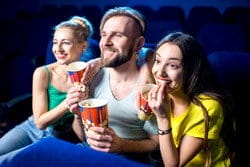 映画館に座ってポップコーンを食べながら映画を楽しむ友人のグループ。