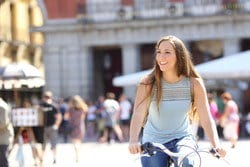 スペインの賑やかな街で自転車に乗る若い女性。