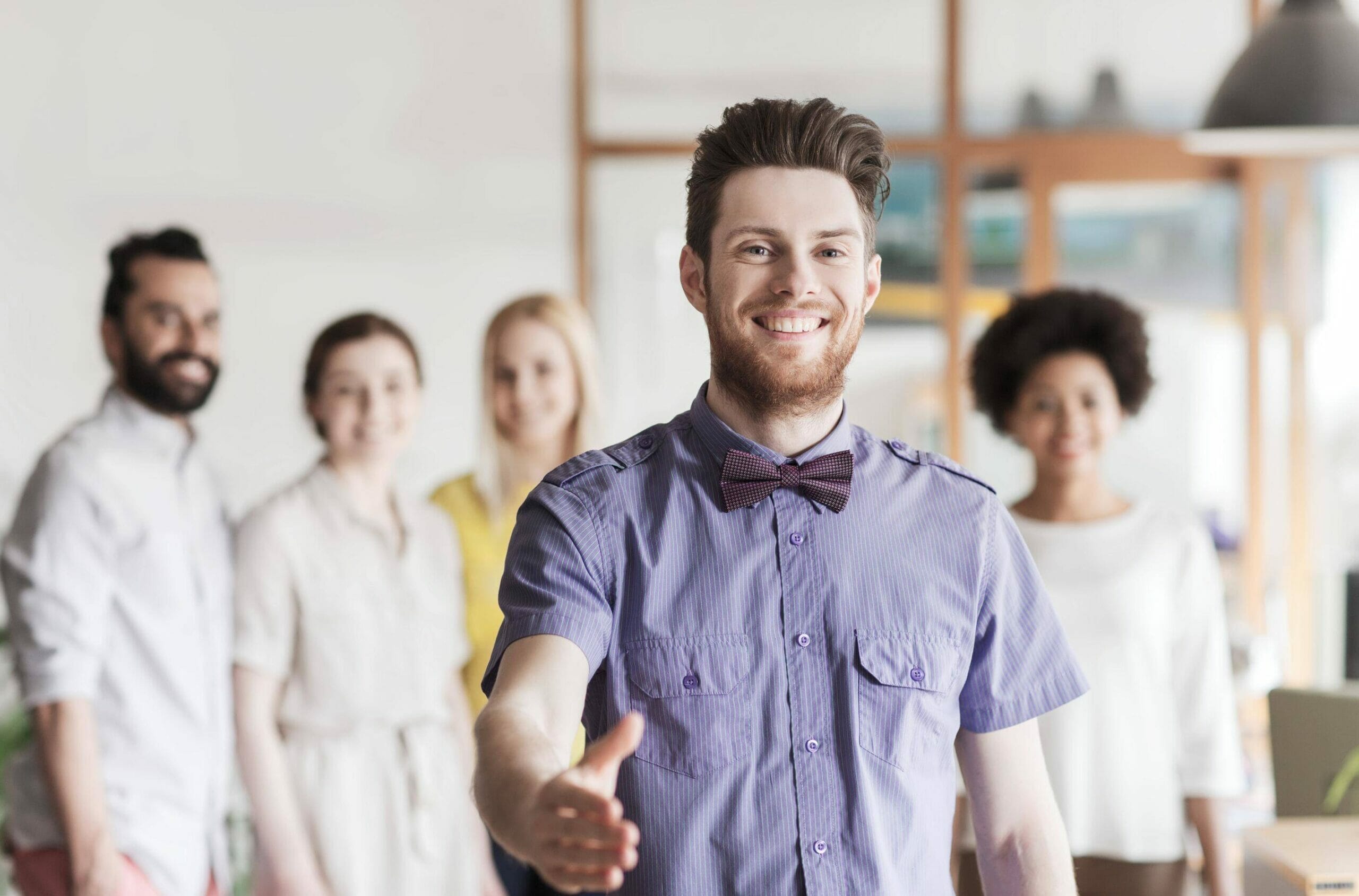 蝶ネクタイをした男性がスペインの服装をした人々の前に立っています。