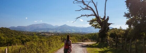 山を背景にスペインの未舗装の道路を歩く女性。