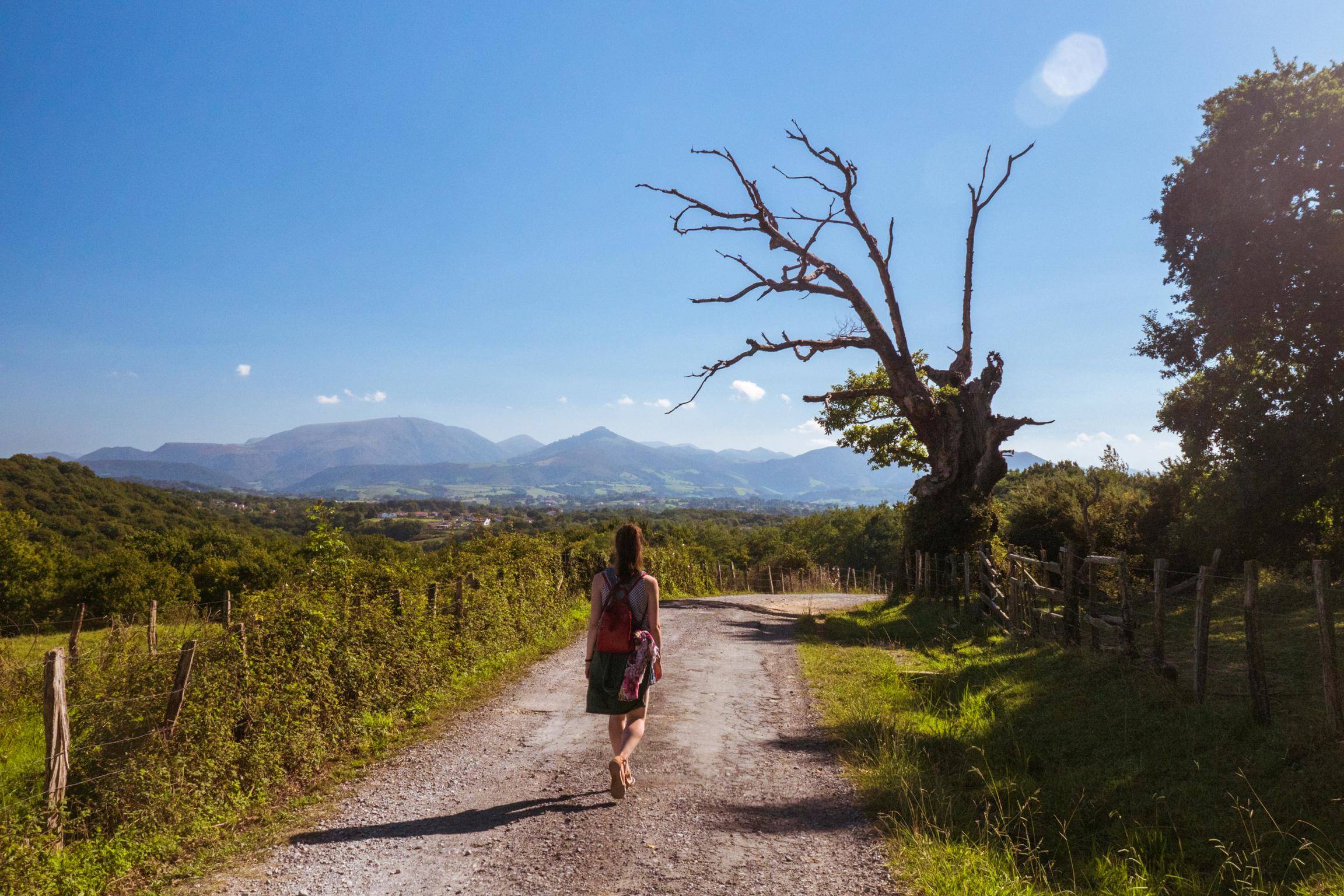 山を背景にスペインの未舗装の道路を歩く女性。 山を背景にスペインの未舗装の道路を歩く女性。