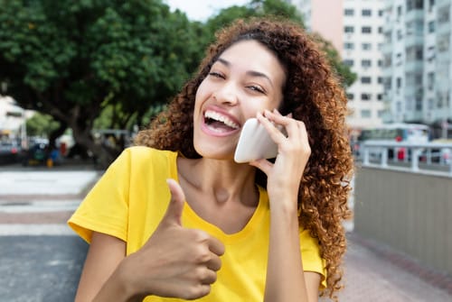 スペインで親指を立てながら電話で話す若い女性。