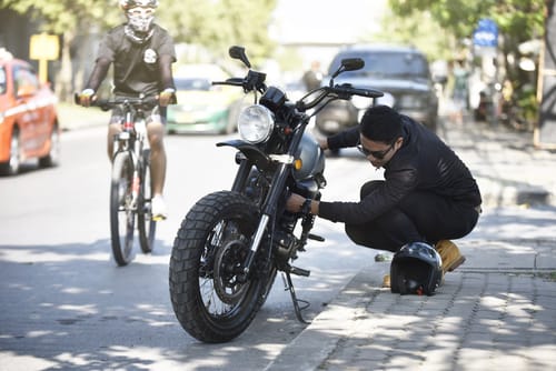 スペインの路上でバイクを修理する男性。