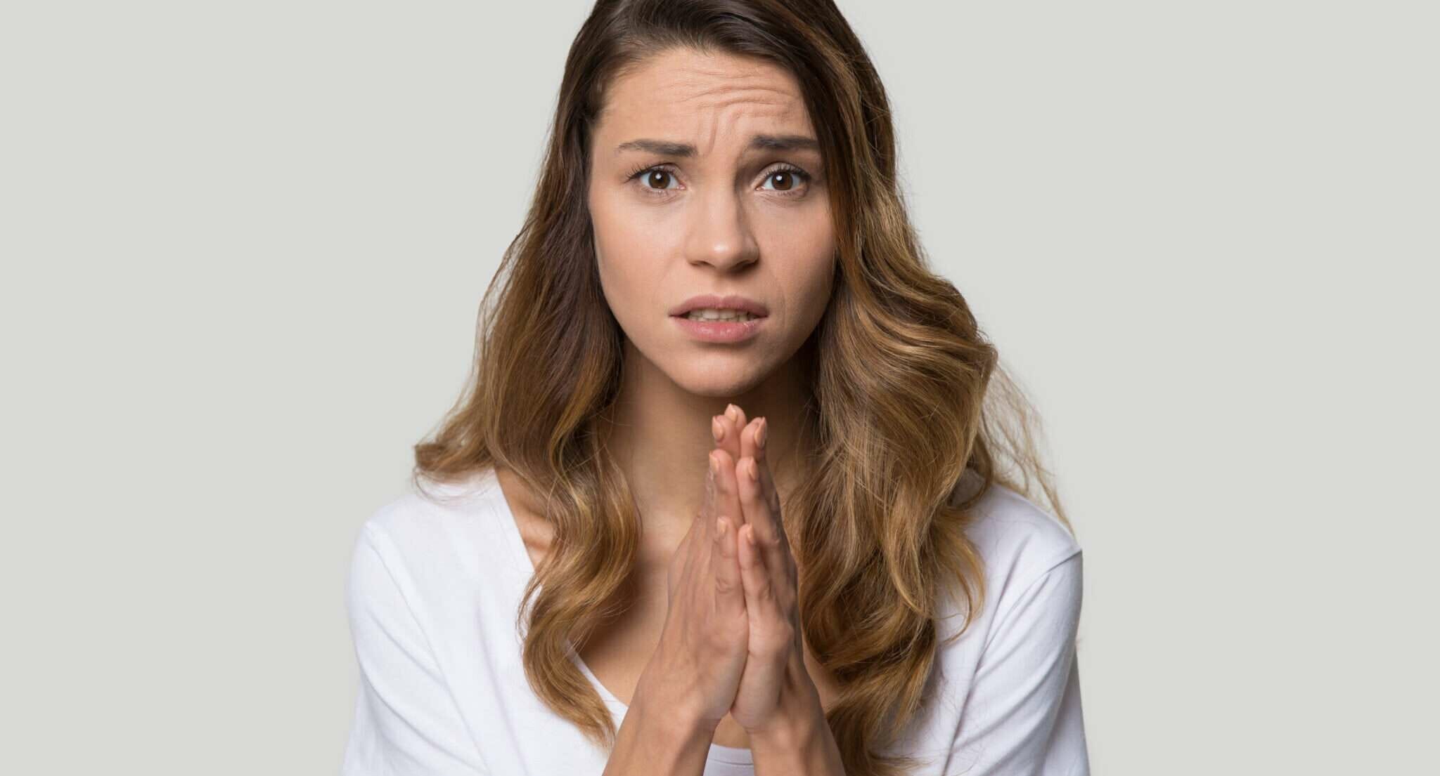 顔の前で手を組むスペインの若い女性。