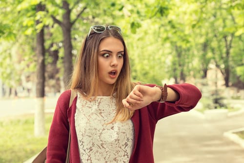 スペインの公園で時計を見ている若い女性。