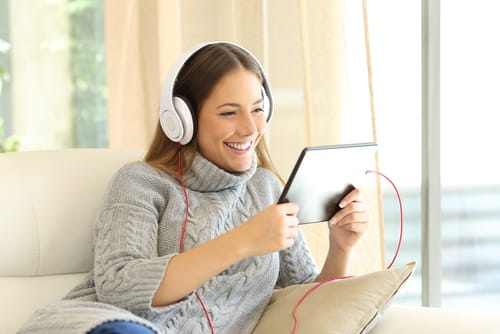 スペインでヘッドフォンを着けた女性がソファに座って音楽を聴いている。