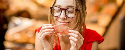 メガネをかけたスペイン人女性が肉を食べている。