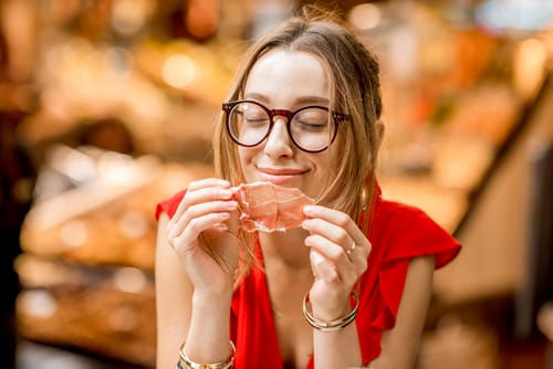 メガネをかけたスペイン人女性が肉を食べている。