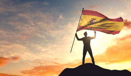 山の頂上でスペイン国旗を掲げるスペイン人男性。 山の頂上でスペイン国旗を掲げるスペイン人男性。