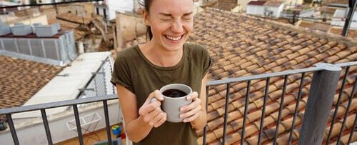 スペインの素晴らしい景色を見渡す絵のように美しい屋上でコーヒーを楽しむ女性。