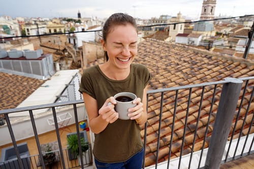 スペインの素晴らしい景色を見渡す絵のように美しい屋上でコーヒーを楽しむ女性。
