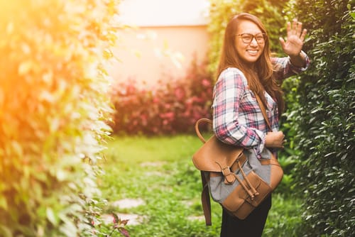 スペイン滞在中に生垣の中でバックパックを振るアジア系の若い女性。