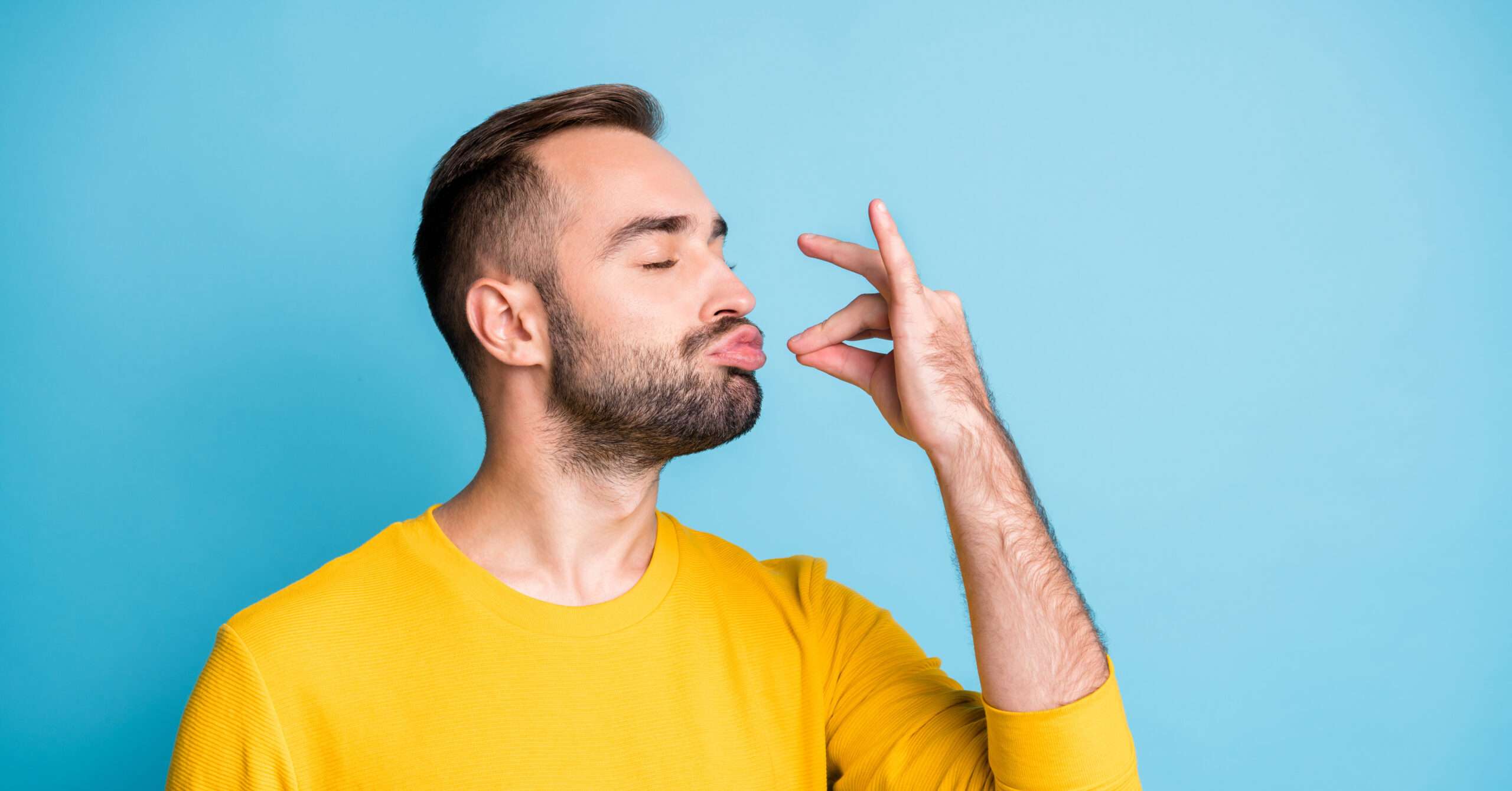 青色の背景に「味」を表現する指のジェスチャーをする男性。