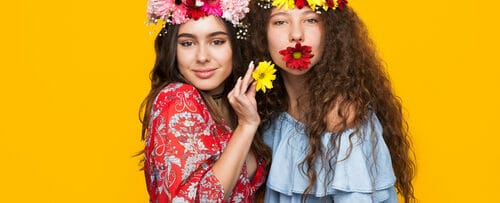 スペインで黄色の背景にポーズをとる、花冠をかぶった2人の若い女性。