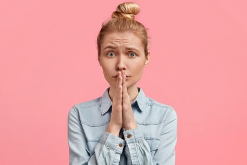 スペインのピンクの背景に手で口を覆う若い女性。 スペインのピンクの背景に手で口を覆う若い女性。