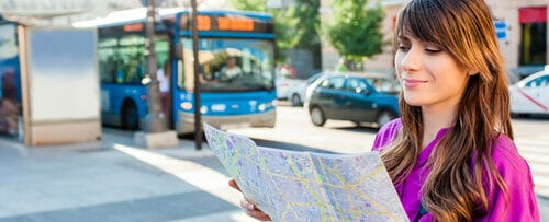 スペイン（スペイン）のバスの前で地図を見ている若い女性。