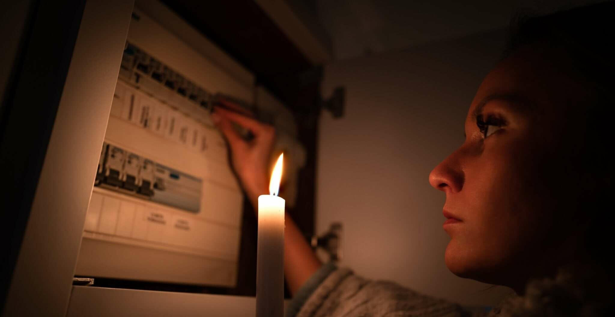 スペインの配電盤の前でろうそくに火を灯す女性。