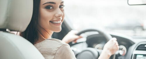 スペインで女性が笑顔で車を運転している。