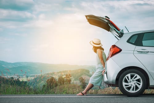 スペインの道路で女性が車のトランクを開けている。