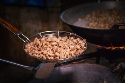 スペイン料理用のストーブの上の鍋で食べ物をかき混ぜている人。