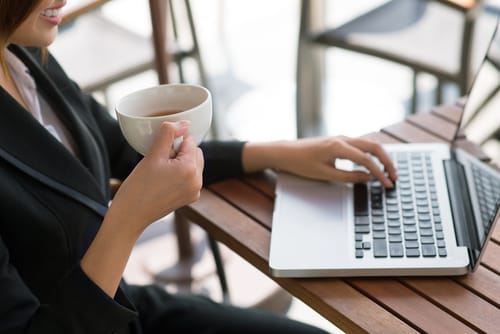 スペインでコーヒーを飲みながらラップトップで仕事をする女性。