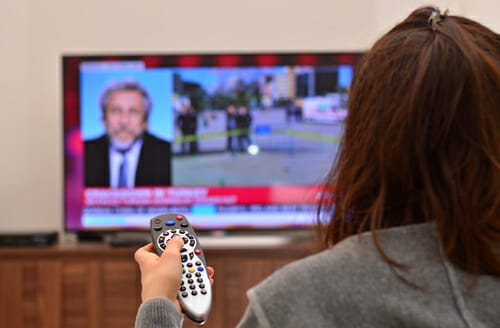 スペインのテレビの前でリモコンを持っている女性。