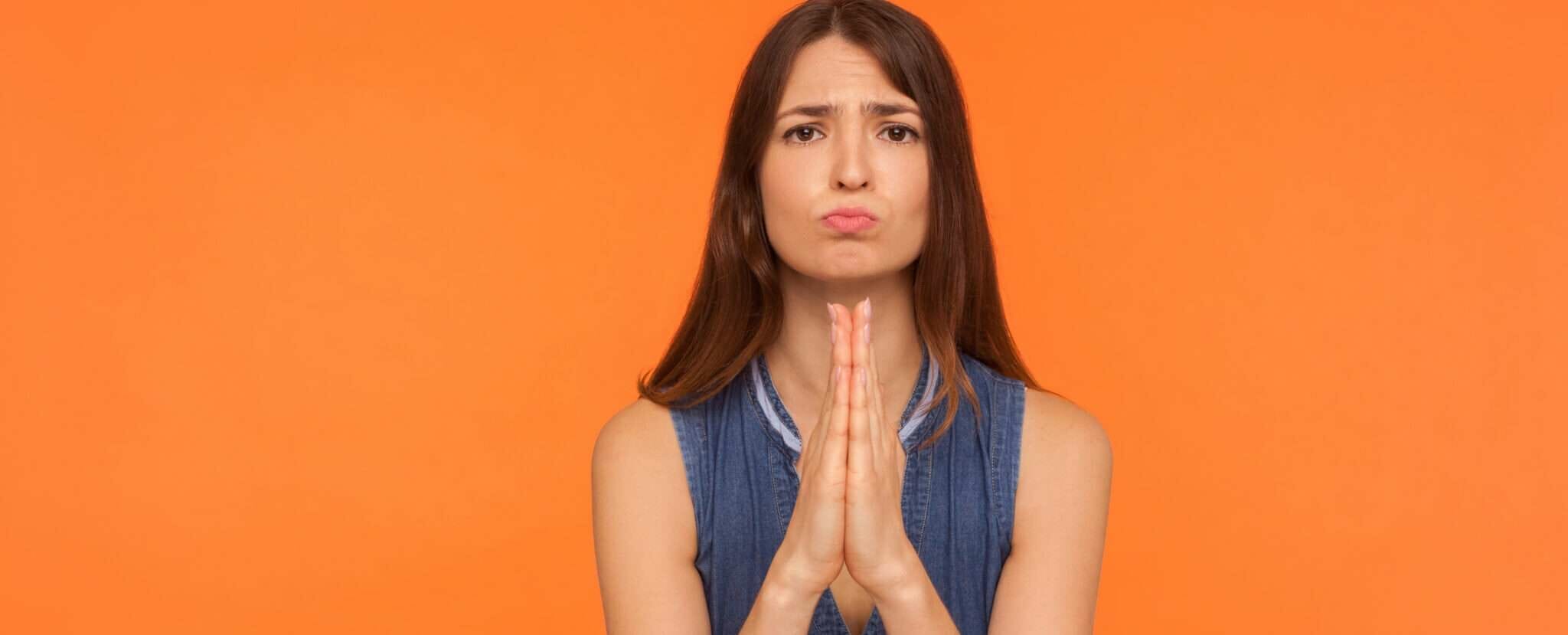 スペイン（スペイン）のオレンジ色の背景に祈る若い女性。