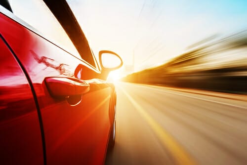 スペインの夕暮れ時に道路を走る赤い車。