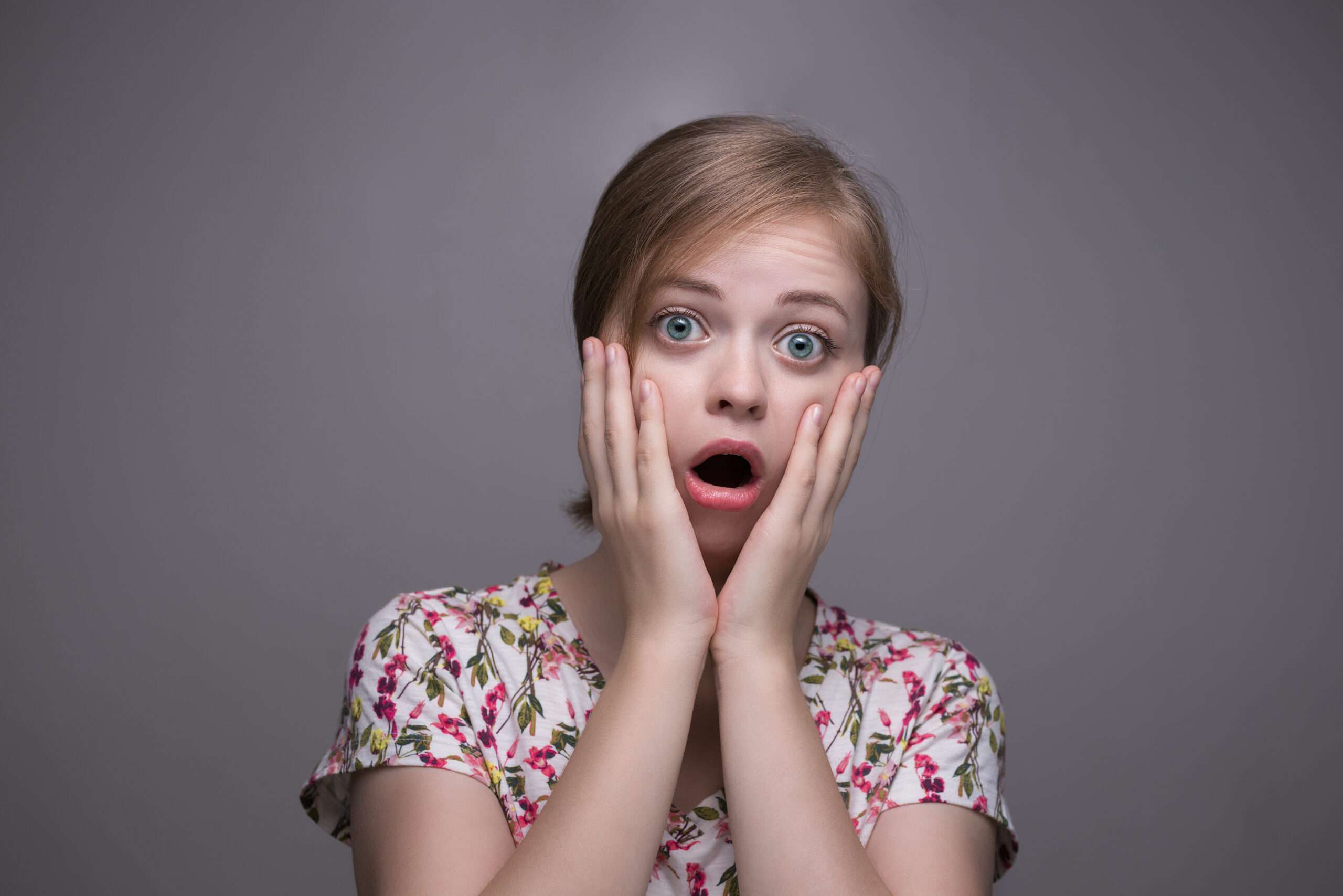 スペイン語で「すごい！信じられない！」とつぶやきながら、両手で顔を覆い、驚きと不信感を表明する若い女性。