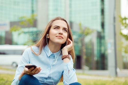 スペインの芝生に座りながら音楽を聴く若い女性。